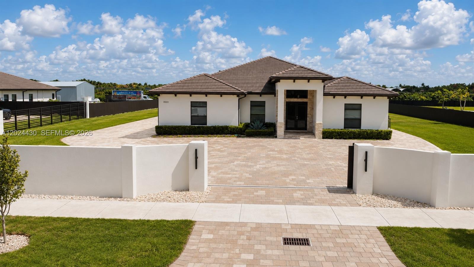 A single-story house with a tiled roof and paved driveway sits behind a white wall — 18321 SW 224th St # 0, Miami FL 33170, MIAMI, FL