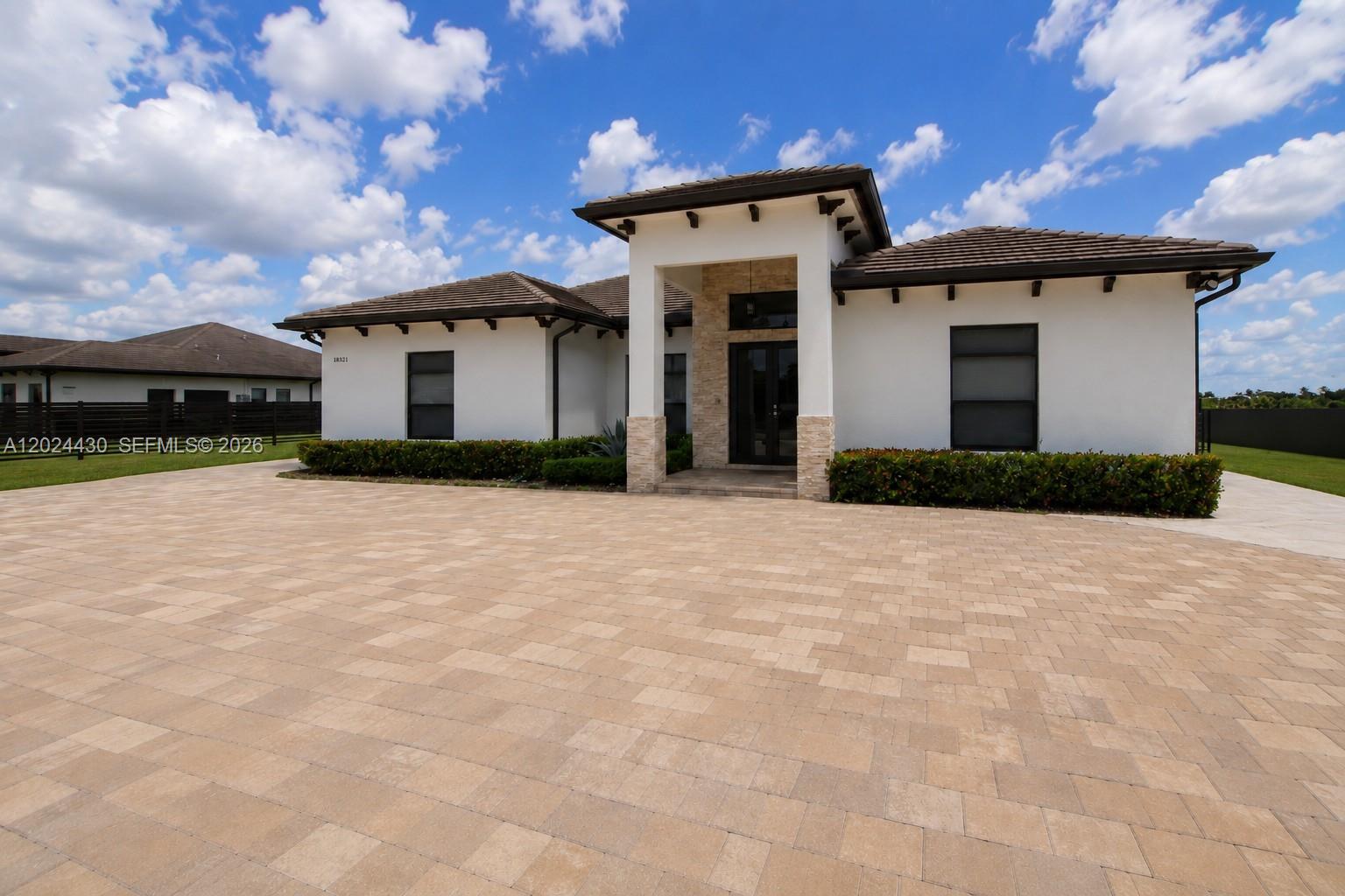 A single-story house with a white stucco exterior, stone accents, and a large paver driveway — 18321 SW 224th St # 0, Miami FL 33170, MIAMI, FL