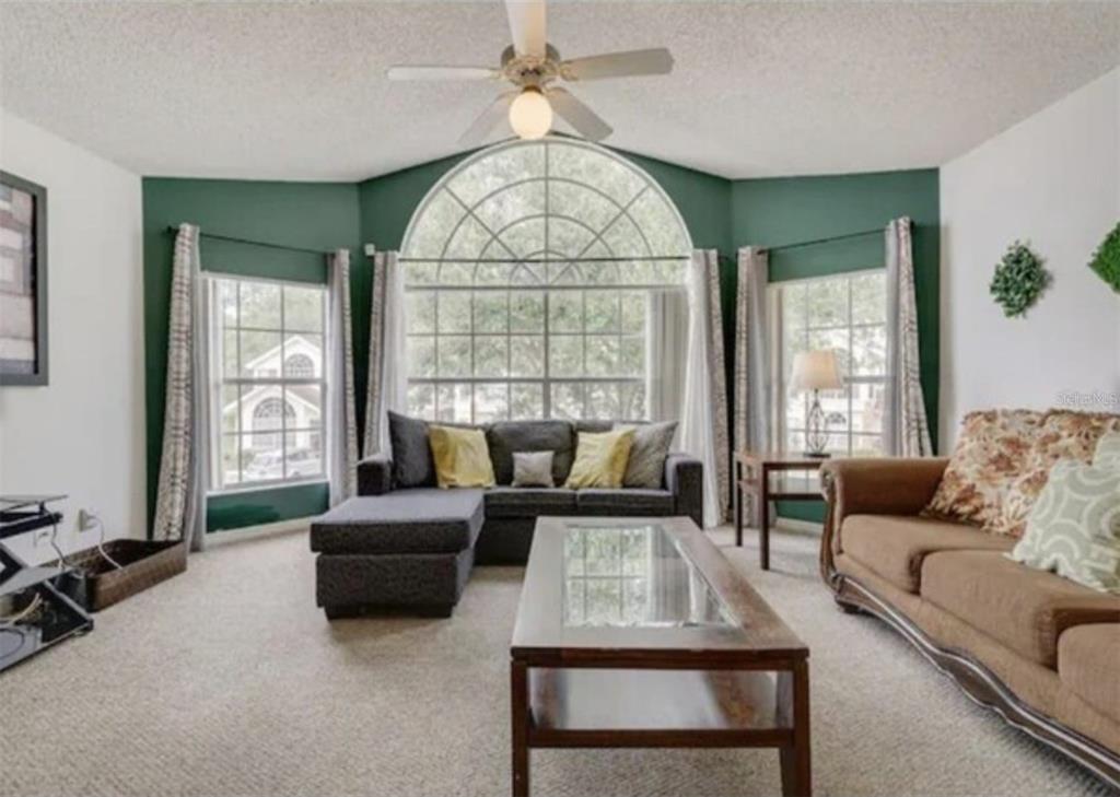 A living room features a large arched window, green accent walls, and two sofas — 5004 LAGUNA BAY CIRCLE UNIT 54, KISSIMMEE, FL
