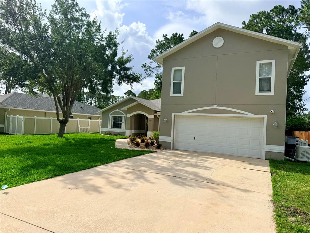 A two-story house with a beige exterior, a two-car garage, and a concrete driveway — 18 BURNING VIEW LANE, PALM COAST, FL