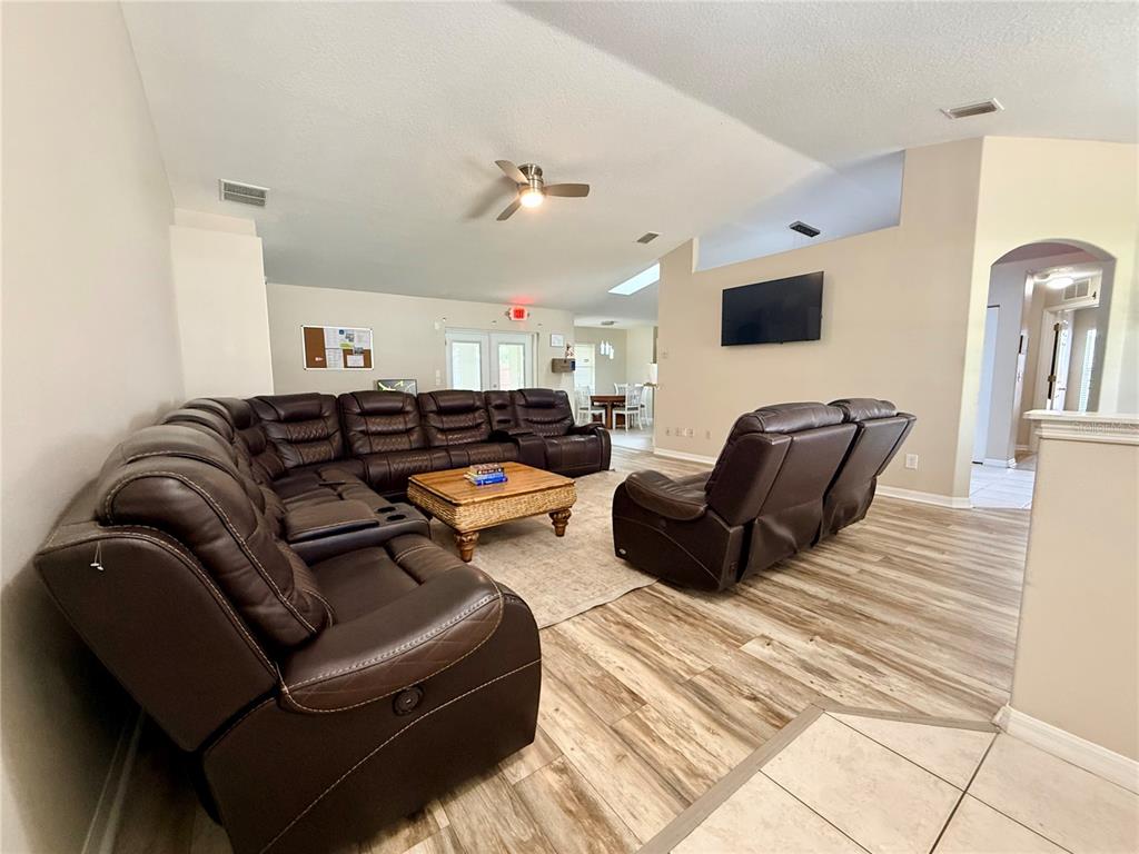 A spacious living room features brown leather sectional seating, a coffee table, and wood-look flooring — 18 BURNING VIEW LANE, PALM COAST, FL