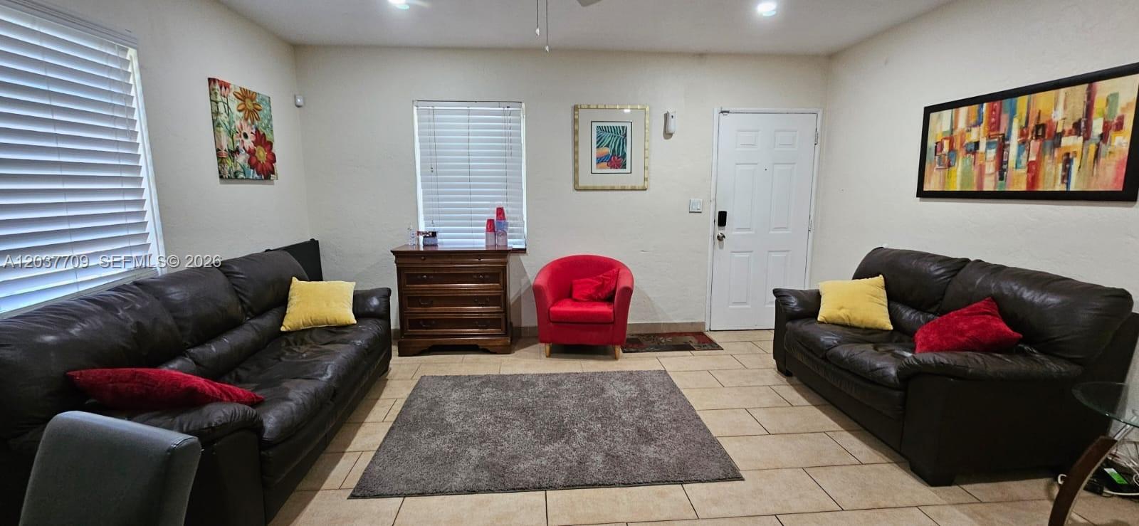 A living room features two dark leather sofas, a red armchair, and tile flooring — 6510 SW 58th Ave, South Miami FL 33143, SOUTH MIAMI, FL