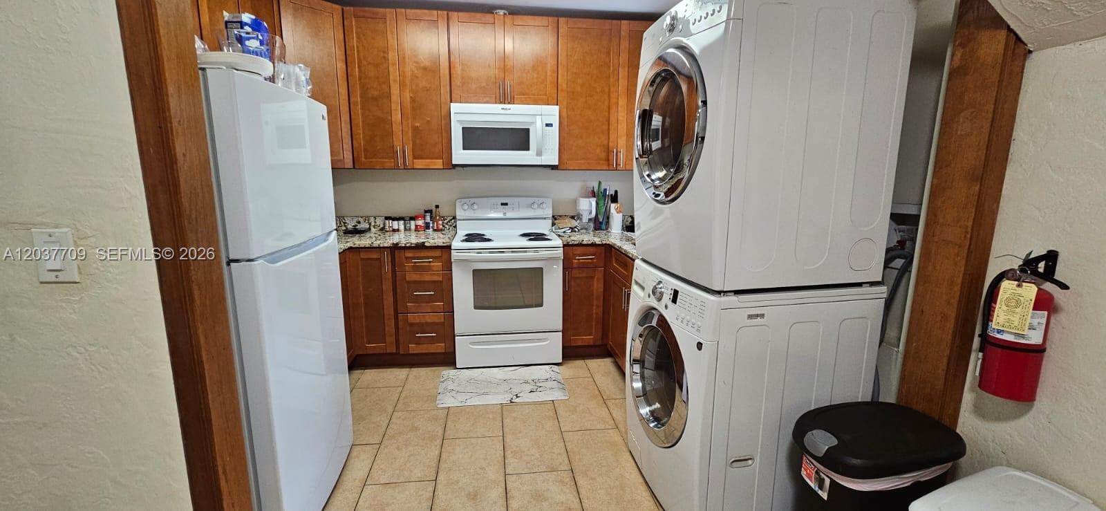 A kitchen features wood cabinets, white appliances, a stacked washer-dryer unit, and tile flooring — 6510 SW 58th Ave, South Miami FL 33143, SOUTH MIAMI, FL