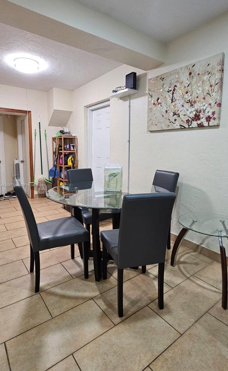 A dining area features a glass table with four grey chairs and tile flooring — 6510 SW 58th Ave, South Miami FL 33143, SOUTH MIAMI, FL