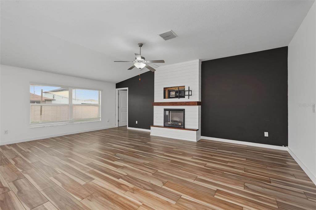 A living room features wood-look tile flooring, a white fireplace, and dark accent walls — 6317 SPIDER LILY WAY, NEW PORT RICHEY, FL