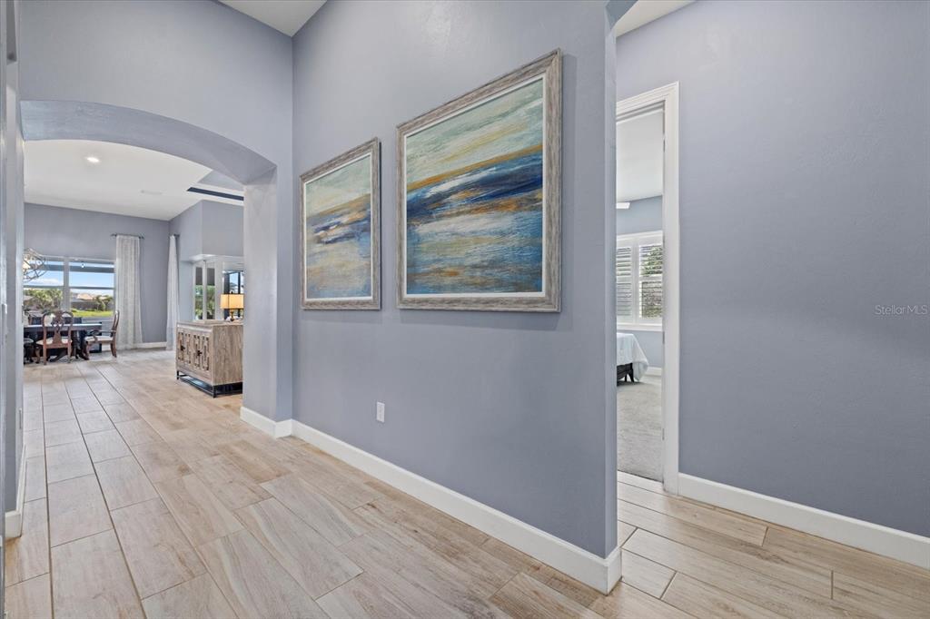 A hallway with light wood-look tile flooring leads to a dining area and bedroom — 12105 SEABROOK AVENUE, BRADENTON, FL