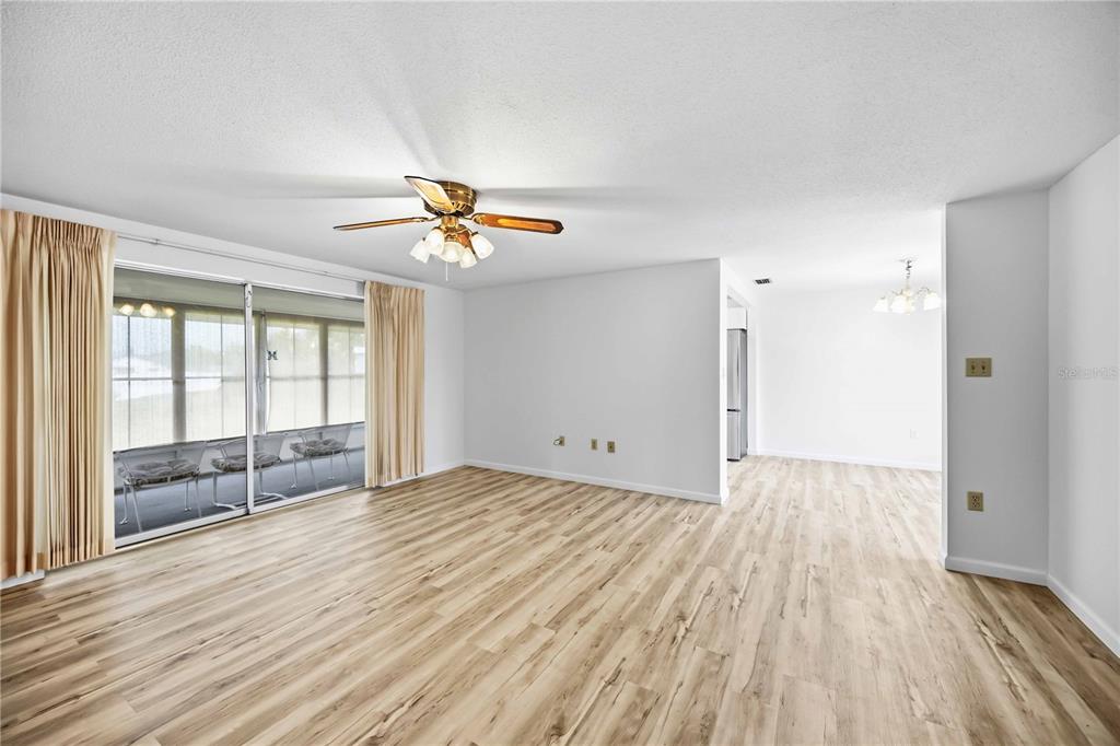 A living room with light wood-look flooring, a ceiling fan, and sliding glass doors — 3249 SUNRISE TRAIL, PORT CHARLOTTE, FL