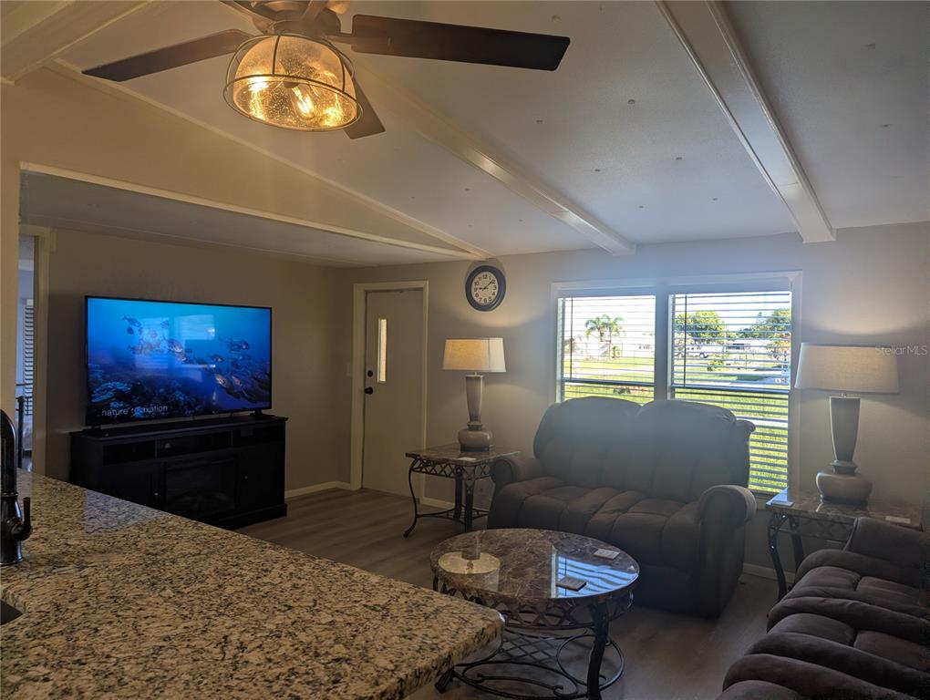 A living room features a granite-topped island, dark brown furniture, and a ceiling fan — 1385 KISKADEE DRIVE, ENGLEWOOD, FL