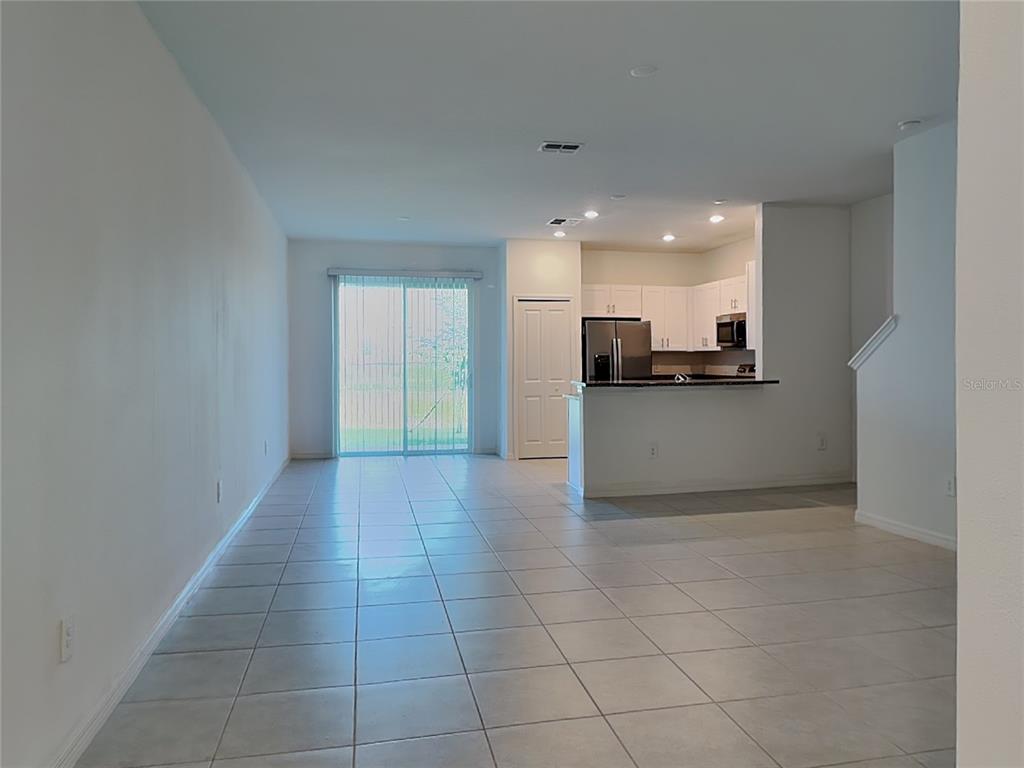 An open-concept living area features light-colored tile flooring, a kitchen with dark countertops, and sliding doors — 9207 BONITA MAR DRIVE, PARRISH, FL
