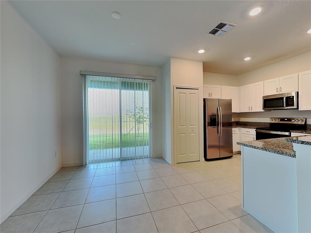 A kitchen and dining area with tile floors, stainless steel appliances, and sliding glass doors — 9207 BONITA MAR DRIVE, PARRISH, FL