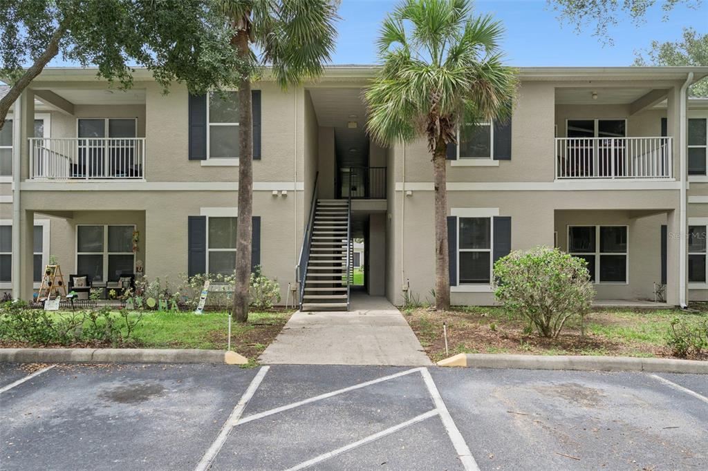A two-story apartment building exterior features a central staircase, balconies, and palm trees — 6005 HEMINGWAY CIRCLE, HAINES CITY, FL