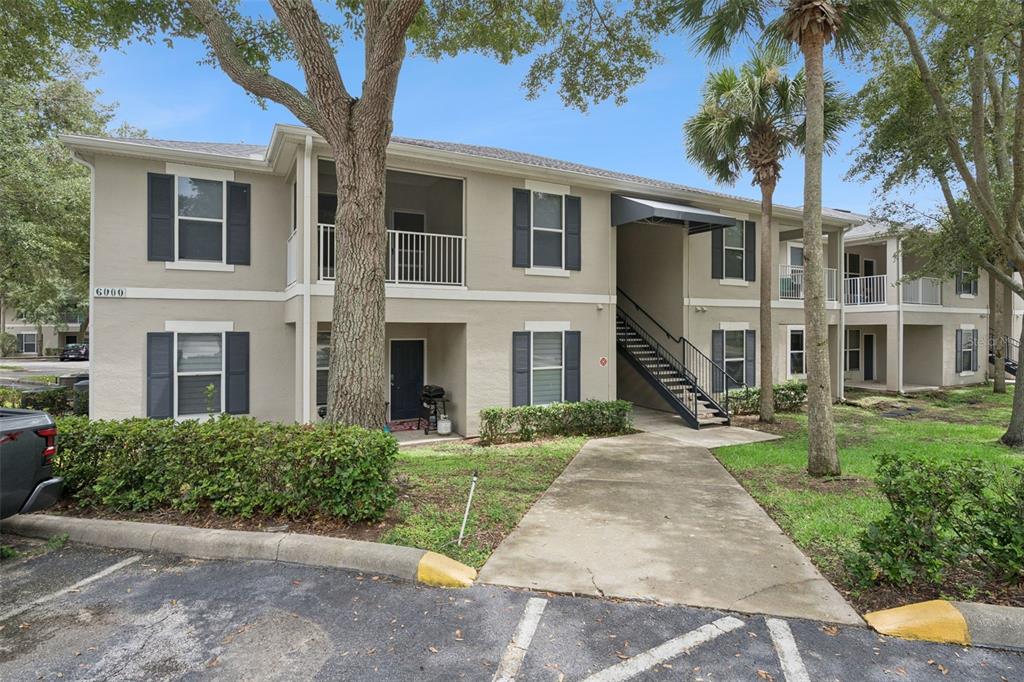 A two-story apartment building with beige stucco siding, dark shutters, and an exterior staircase — 6005 HEMINGWAY CIRCLE, HAINES CITY, FL