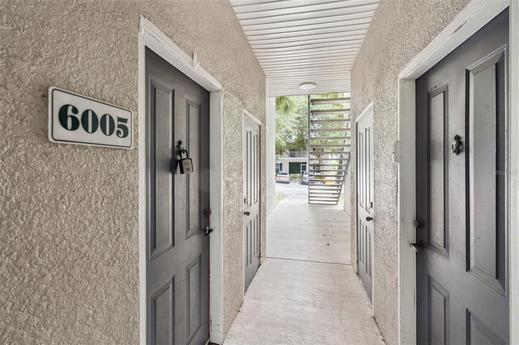 An exterior hallway features two gray apartment doors with white trim and a metal staircase — 6005 HEMINGWAY CIRCLE, HAINES CITY, FL