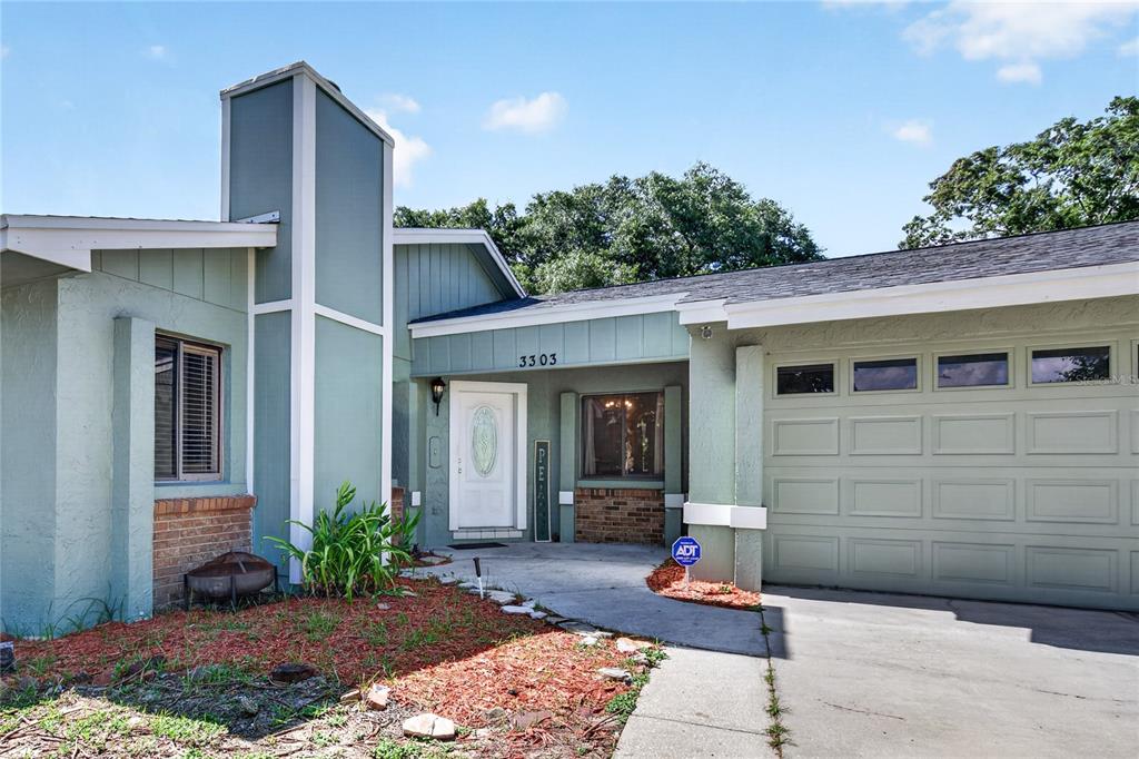 A single-story house with light green siding, a brick accent wall, and an attached garage — 3303 FOXBORO COURT, MOUNT DORA, FL