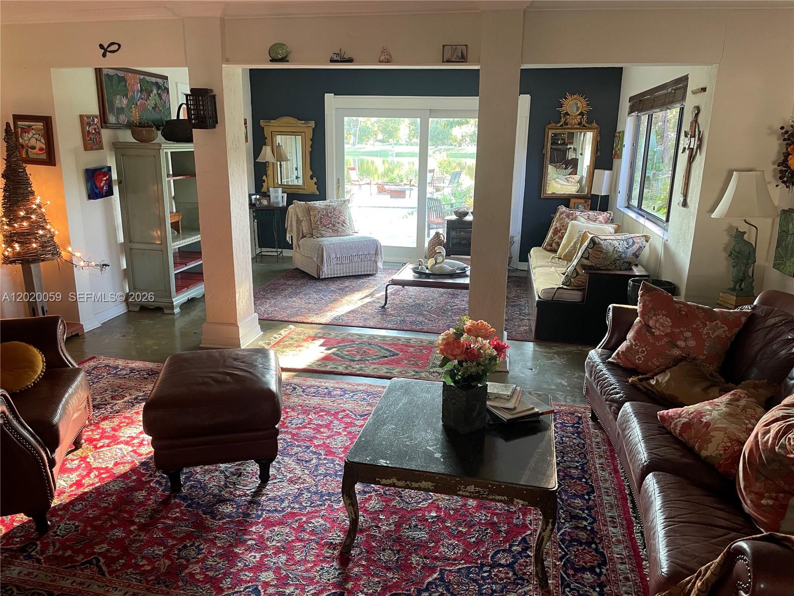 A living room features multiple seating areas, patterned rugs, and a view of a pond — 6703 Oneco Way, Fort Pierce FL 34951, FORT PIERCE, FL