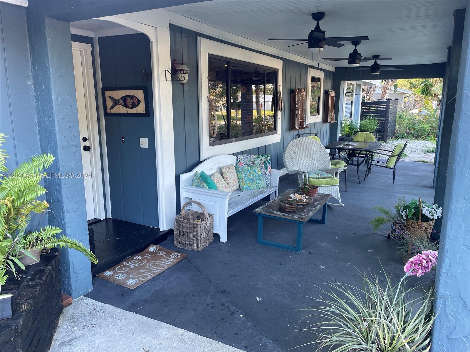 A covered porch features blue siding, a white bench, outdoor seating, and ceiling fans — 6703 Oneco Way, Fort Pierce FL 34951, FORT PIERCE, FL