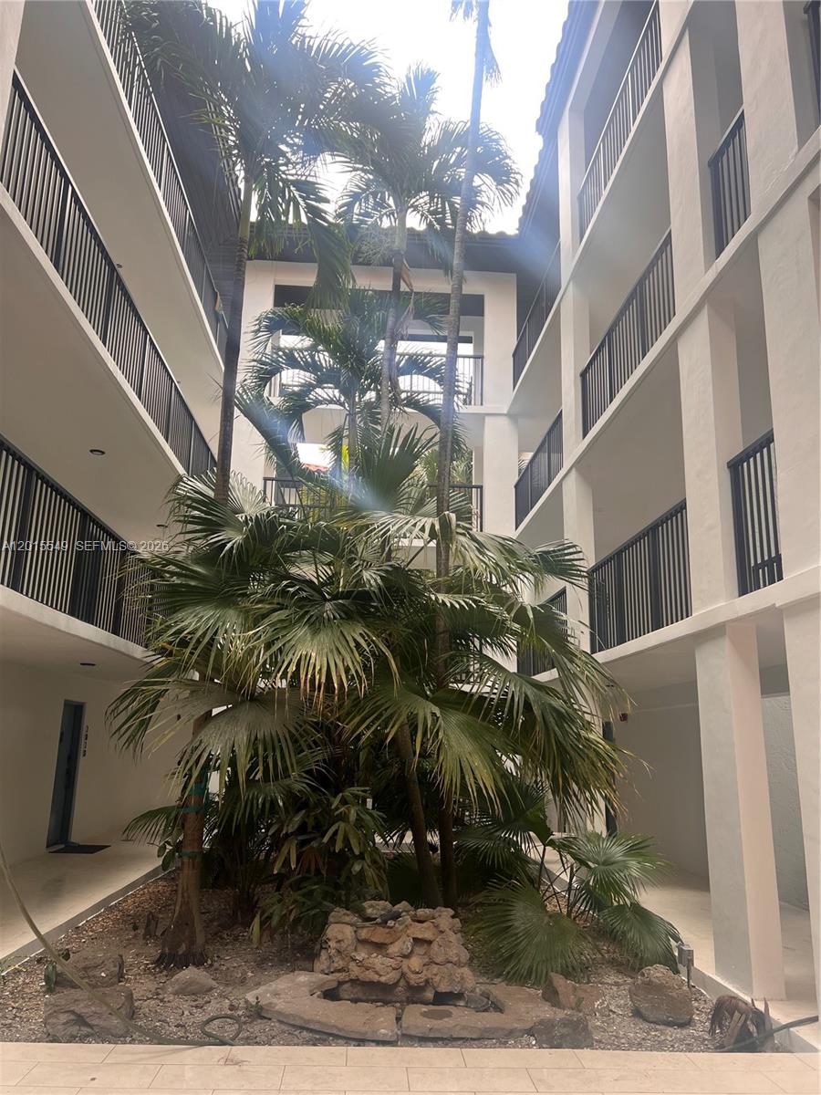 An open-air courtyard features a central palm tree garden surrounded by multi-story apartment balconies — 55 Ocean Lane Dr # 3030, Key Biscayne FL 33149, KEY BISCAYNE, FL
