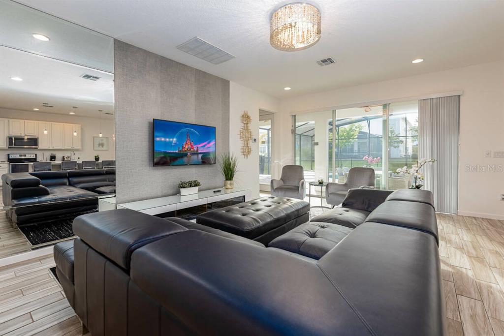 A living room features a large black sectional sofa, a wall-mounted television, and sliding doors — 2678 CALISTOGA AVENUE, KISSIMMEE, FL