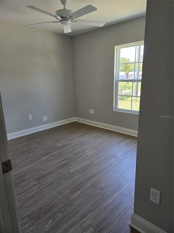 An empty room features gray walls, wood-look flooring, a ceiling fan, and a single window — 4437 BESSIE CIRCLE E, JACKSONVILLE, FL