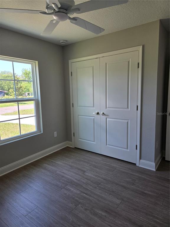 A bedroom with gray walls, wood-look flooring, a ceiling fan, and white double closet doors — 4437 BESSIE CIRCLE E, JACKSONVILLE, FL