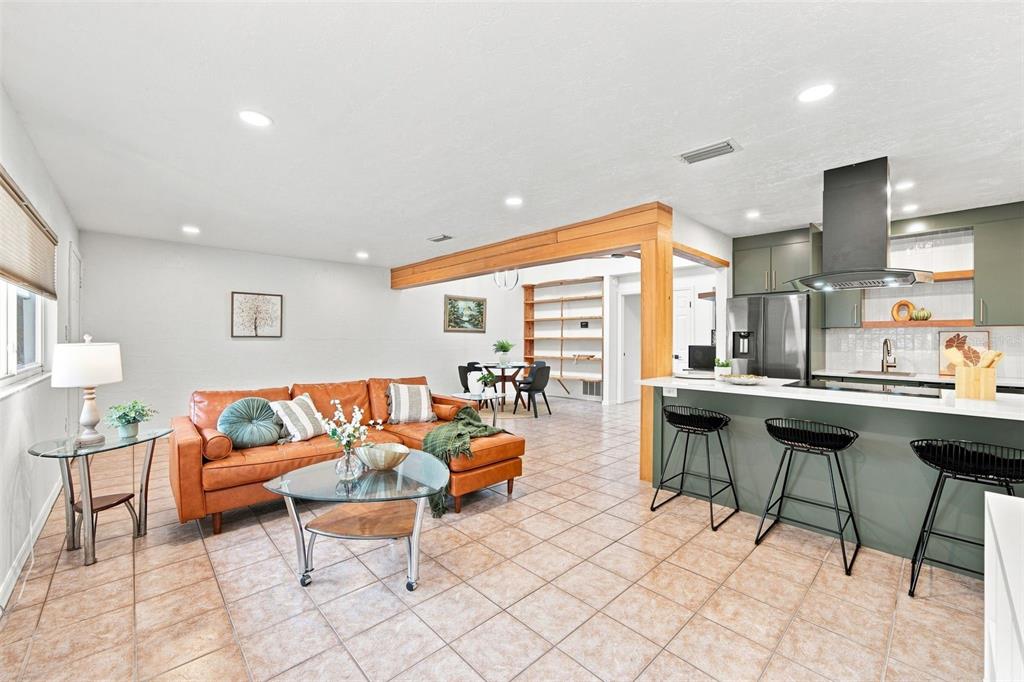 An open-concept living room and kitchen feature tile floors, a leather sectional, and wood beams — 747 SE 2ND PLACE UNIT 2, GAINESVILLE, FL