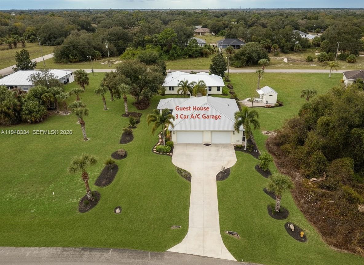An aerial view shows a detached guest house with a three-car garage on a grassy lot — 1197 April Ave, La Belle FL 33935, LA BELLE, FL