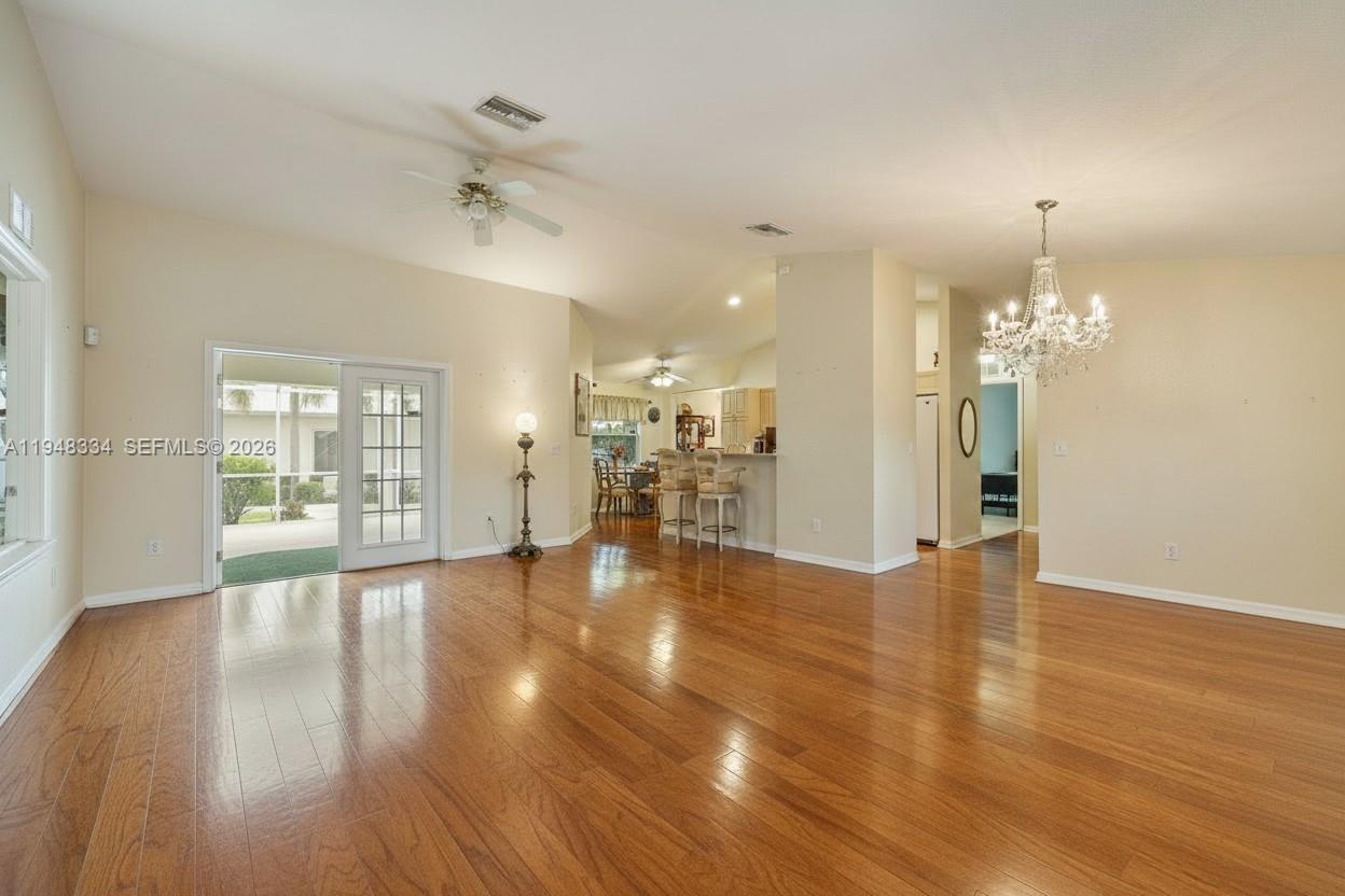 A spacious living area features hardwood floors, a chandelier, and sliding glass doors to outside — 1197 April Ave, La Belle FL 33935, LA BELLE, FL
