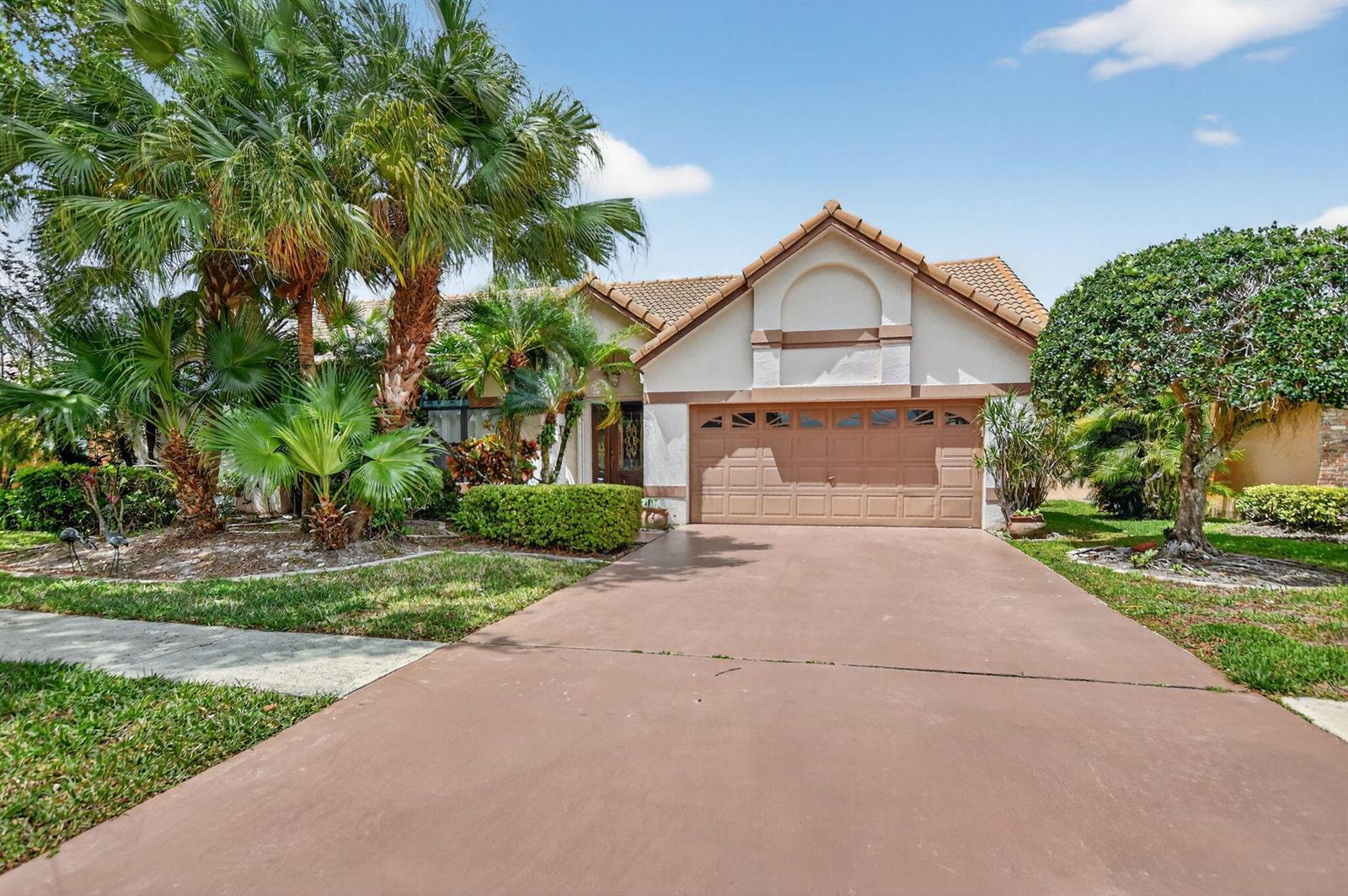 A single-story house with a brown garage door, tiled roof, and palm trees in front — 20174 Back Nine Drive, Boca Raton FL 33498, BOCA RATON, FL