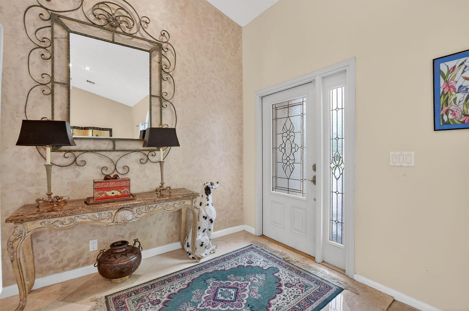 An entryway features a console table, a large ornate mirror, and a decorative dog statue — 20174 Back Nine Drive, Boca Raton FL 33498, BOCA RATON, FL