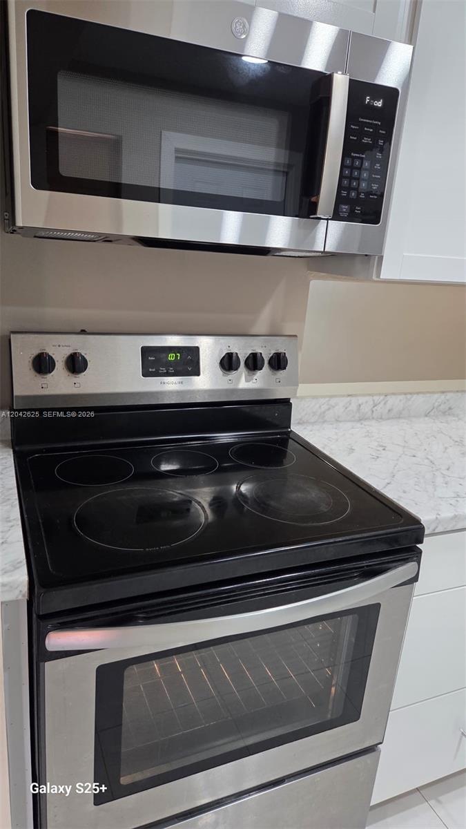 A stainless steel microwave sits above a Frigidaire electric range in a kitchen — 251 NE 187th St # 809, Miami FL 33179, MIAMI, FL