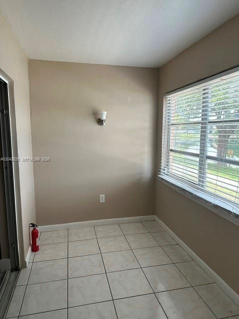 A room with light-colored tile flooring, a wall-mounted light fixture, and a large window — 251 NE 187th St # 809, Miami FL 33179, MIAMI, FL