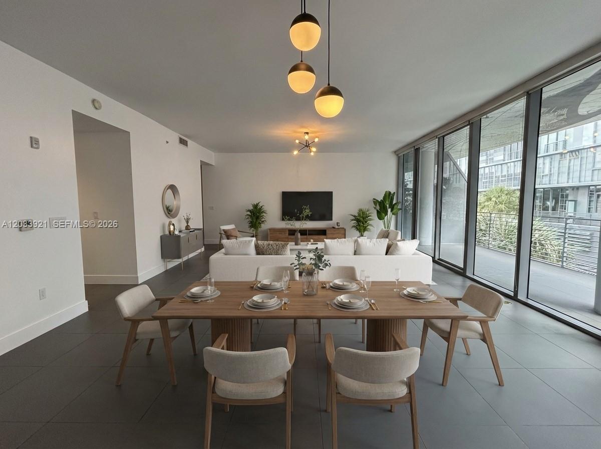A modern open-concept living and dining area features tile floors, floor-to-ceiling windows, and pendant lighting — 250 NW 24th St # 3C, Miami FL 33127, MIAMI, FL