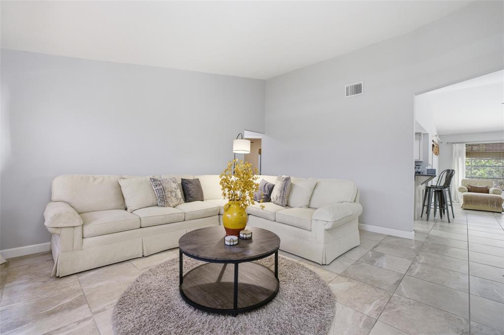 A living room features a cream sectional sofa, a round coffee table, and tile flooring — 6856 FAIRVIEW STREET, FORT MYERS, FL
