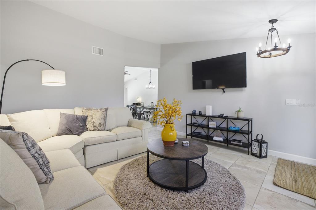 A living room features a sectional sofa, a round coffee table, and a wall-mounted television — 6856 FAIRVIEW STREET, FORT MYERS, FL