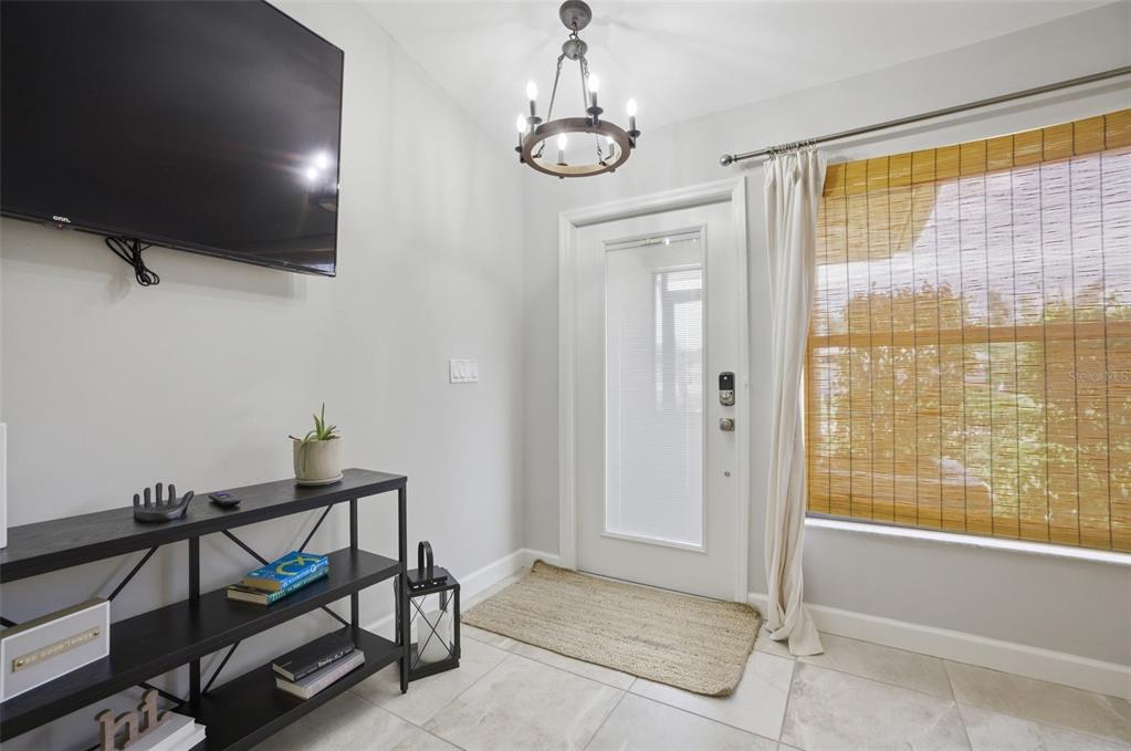 A bright entryway features a television, a black metal console table, and a glass-paneled door — 6856 FAIRVIEW STREET, FORT MYERS, FL