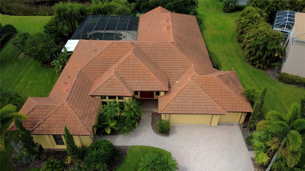 An aerial view of a single-story house with a tile roof and a screened pool — 406 PETREL TRAIL, BRADENTON, FL
