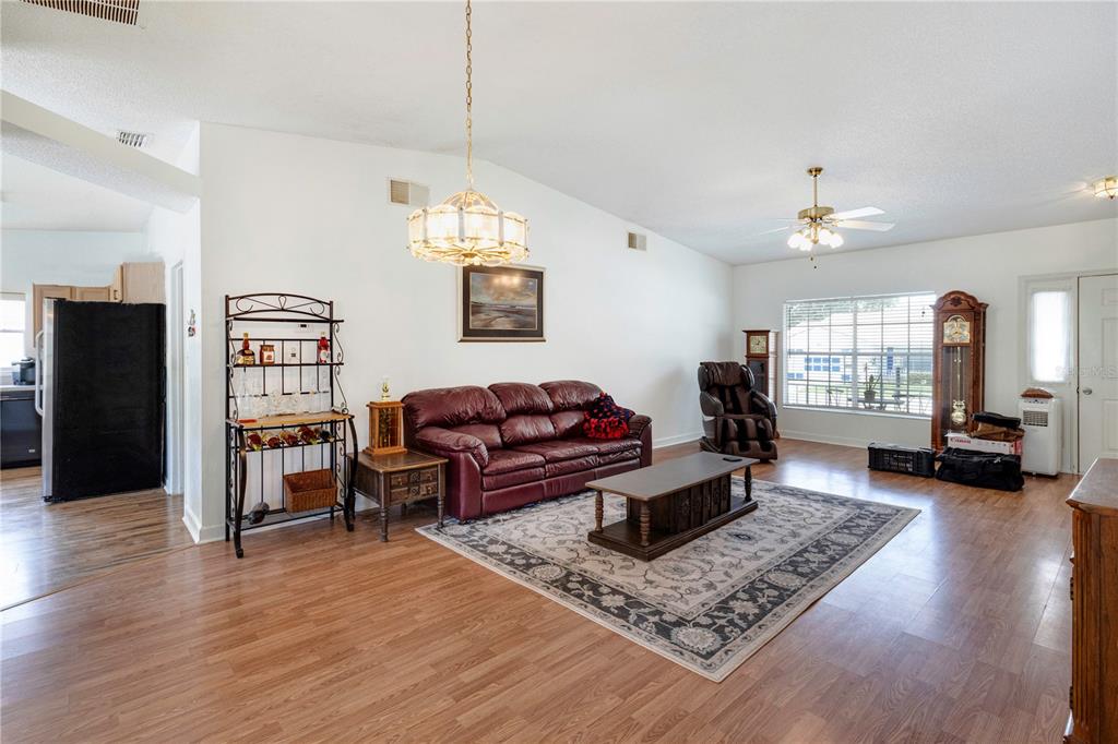 A living room features a burgundy leather sofa, a coffee table, and wood-look flooring — 5030 EL DESTINO DRIVE, LEESBURG, FL