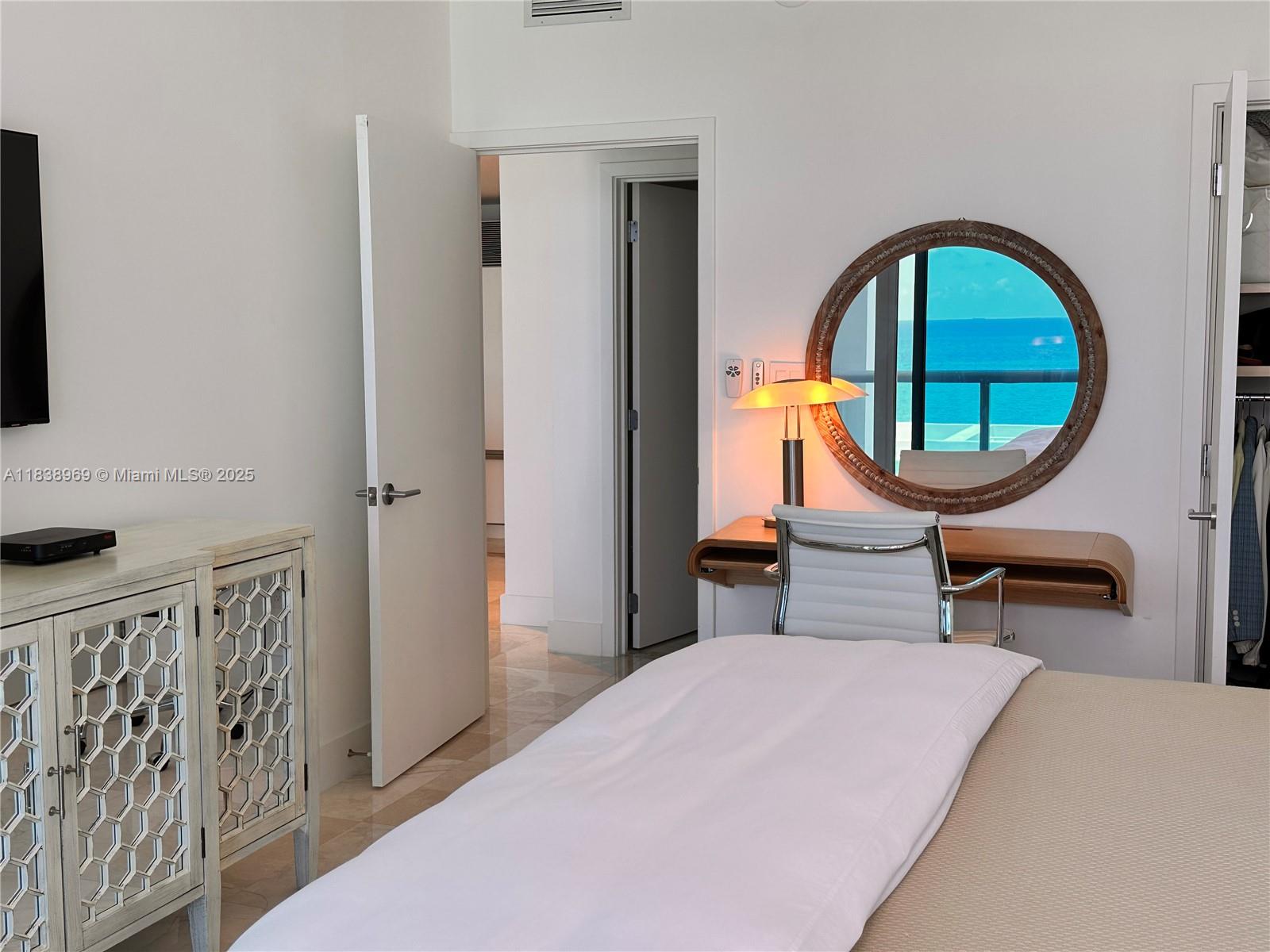 A bedroom features a white cabinet, a desk with a mirror, and an ocean view — 6799 Collins Ave # 804, Miami Beach FL 33141, MIAMI BEACH, FL