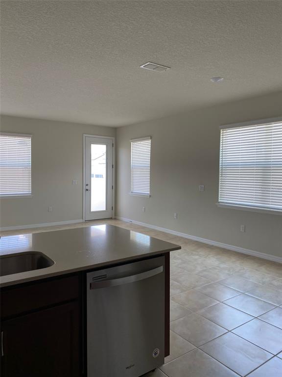 A kitchen island with a stainless steel dishwasher faces a room with tile floors — 2101 GOPHER TORTOISE TERRACE, OAKLAND, FL