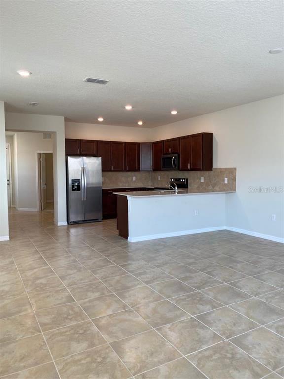 A kitchen with dark wood cabinets, stainless steel appliances, and a tiled floor — 2101 GOPHER TORTOISE TERRACE, OAKLAND, FL