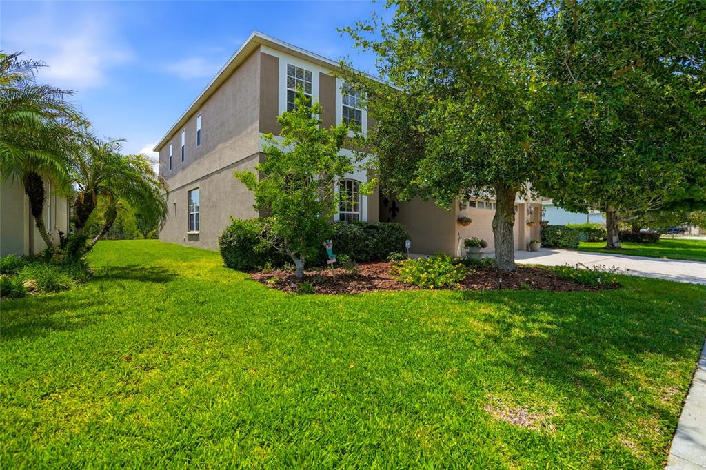 A two-story tan stucco house with a green lawn and trees in the front yard — 9643 ASBEL ESTATES STREET, LAND O LAKES, FL