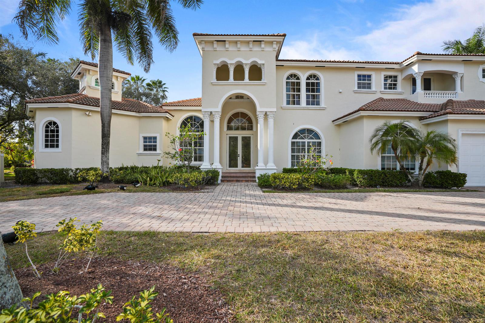 A two-story Mediterranean-style house features a paved driveway, arched windows, and a columned entryway — 3201 E Stonebrook Circle, Davie FL 33330, DAVIE, FL