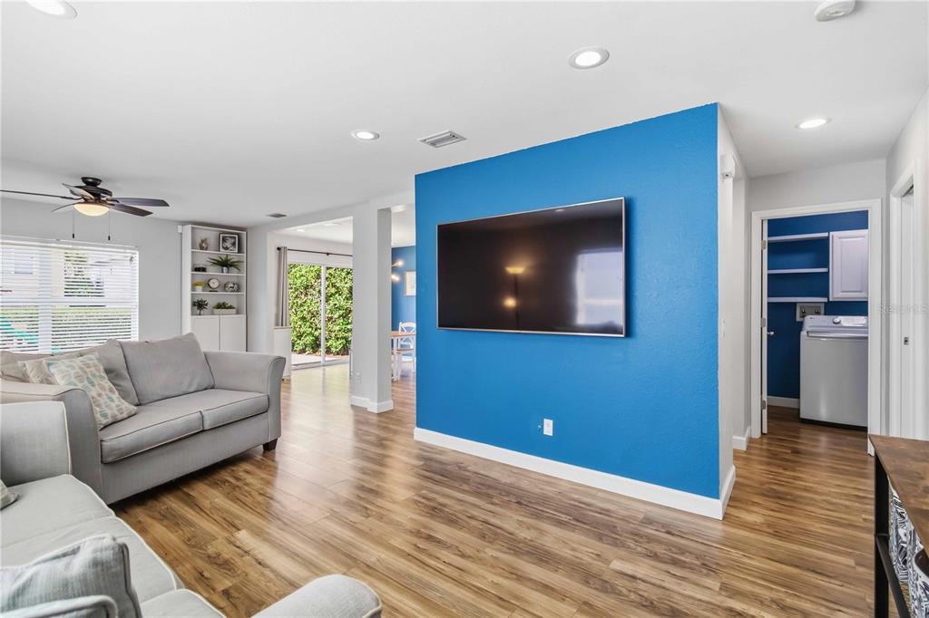 A living room features a blue accent wall with a mounted television and wood flooring — 7148 CHATUM LIGHT RUN, BRADENTON, FL