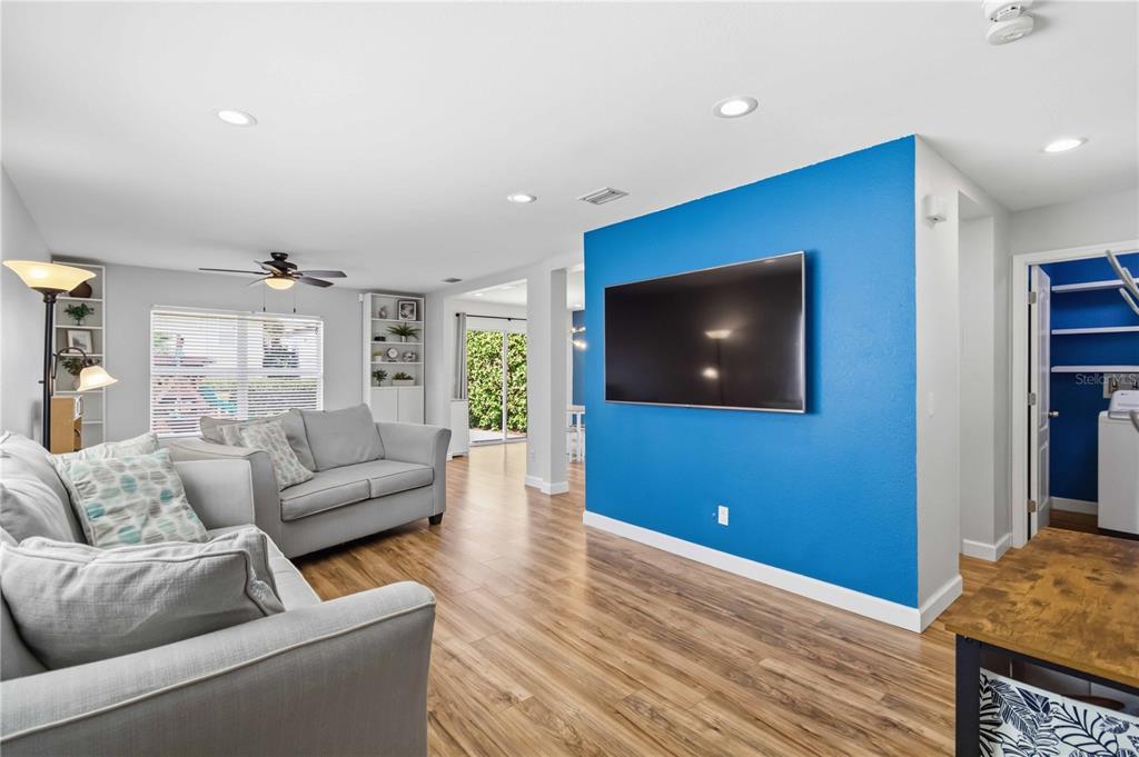 A living room features light wood flooring, a blue accent wall with a television, and sofas — 7148 CHATUM LIGHT RUN, BRADENTON, FL