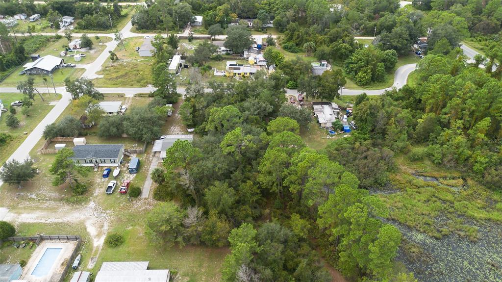 An aerial view shows a wooded residential lot with several houses and a nearby pond — 0 CEDAR STREET, PAISLEY, FL