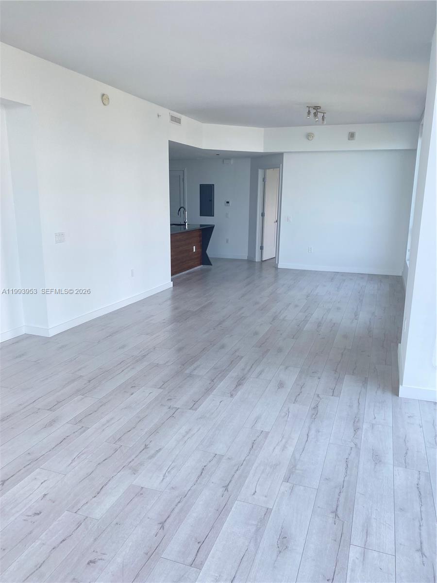 An open-concept living area features light wood-look flooring, white walls, and a kitchen island — 601 NE 27TH ST # 1107, Miami FL 33137, MIAMI, FL
