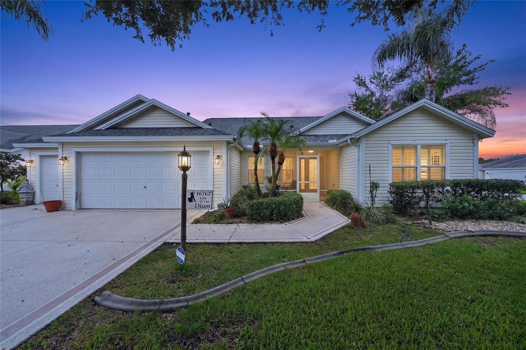 A single-story house with light-colored siding, a two-car garage, and a landscaped front walkway — 16767 SE 77TH NORTHRIDGE COURT, THE VILLAGES, FL
