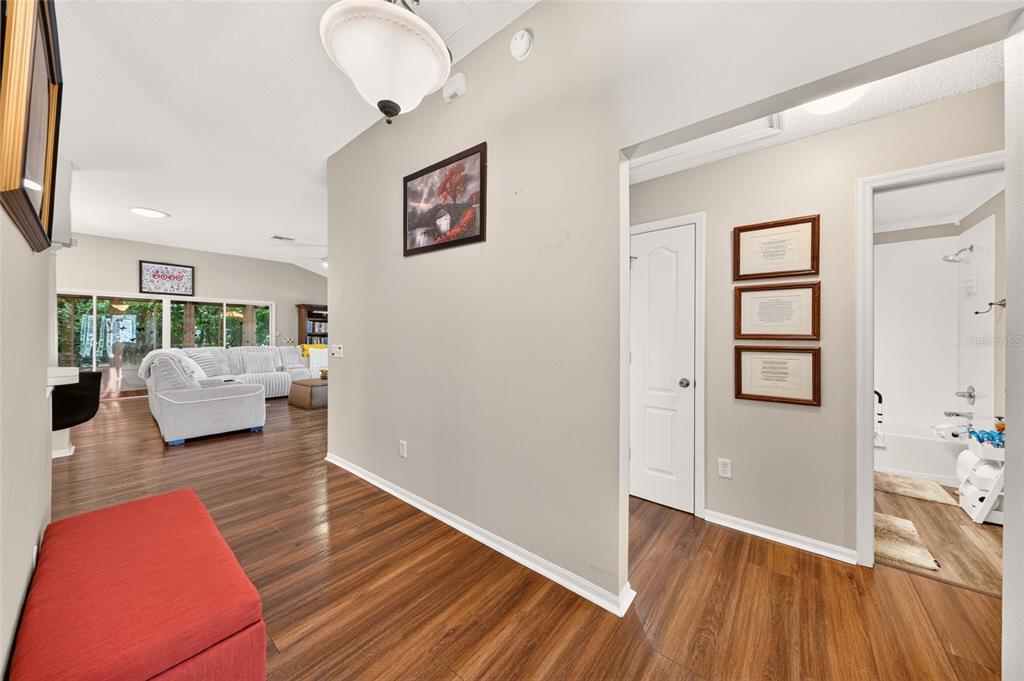 A hallway with wood-look flooring leads to a living area and a bathroom — 16767 SE 77TH NORTHRIDGE COURT, THE VILLAGES, FL