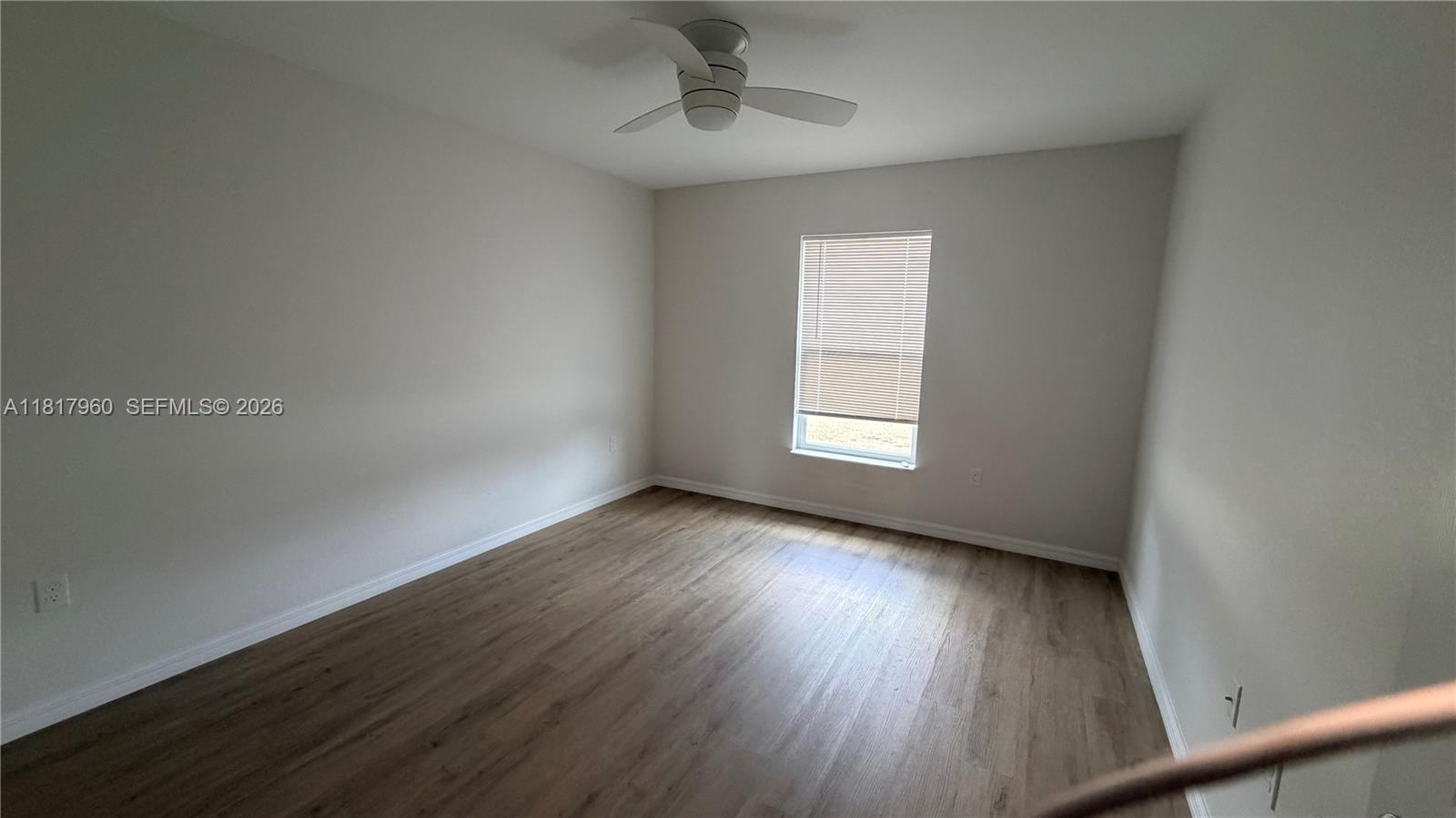 An empty bedroom features light-colored walls, wood-look flooring, a ceiling fan, and a single window — 7006 San Bruno Dr, Sebring FL 33872, SEBRING, FL
