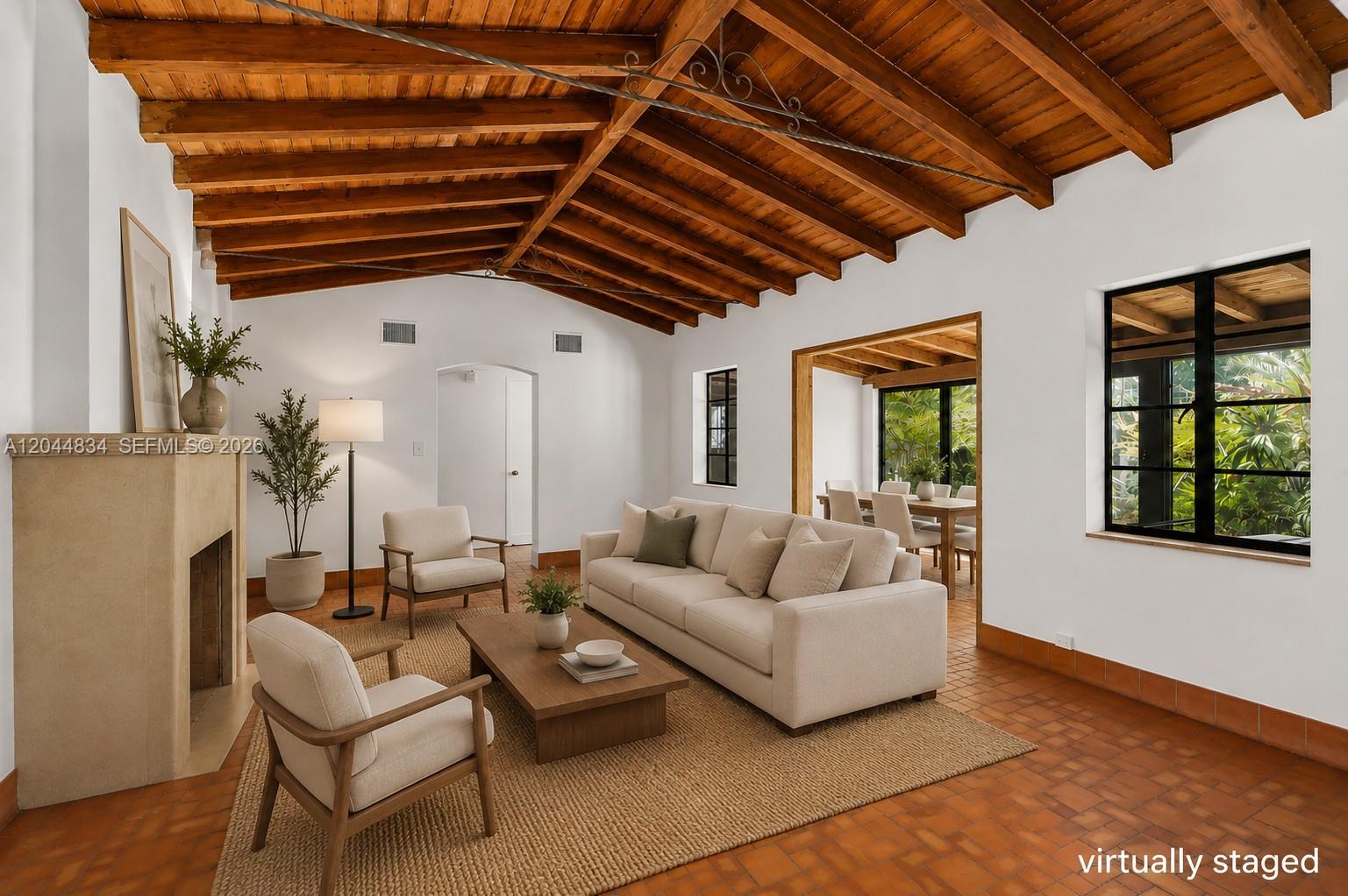 A living room features a vaulted wood-beam ceiling, terracotta tile floors, and a stone fireplace — 5390 Sunset Dr, Miami FL 33143, MIAMI, FL